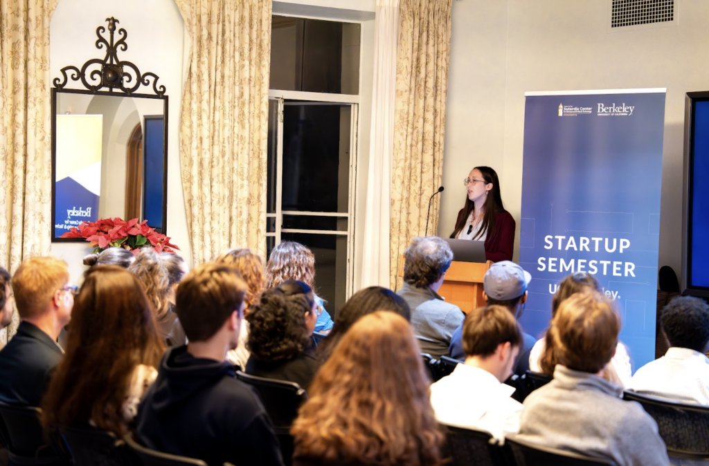 Mar Navarro speaks at the Berkeley Startup Semester Program graduation in an auditorium of people.